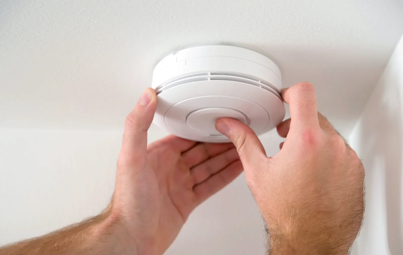 Smoke alarm being fitted to the ceiling